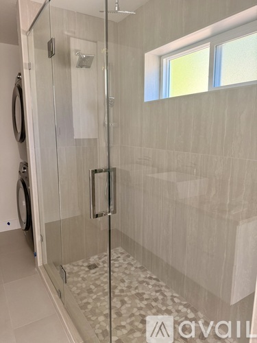 A bathroom with a glass shower door and a tiled floor.