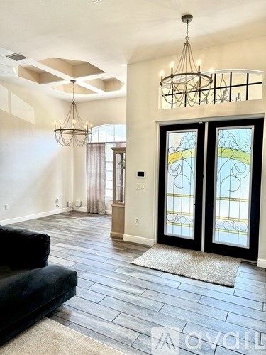 A living room with a black couch and a chandelier.