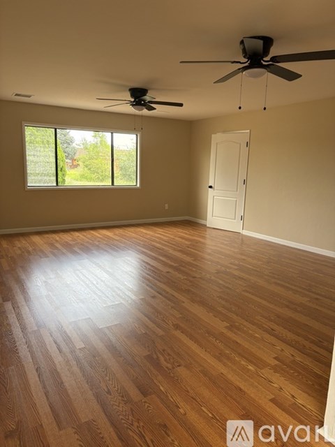 A room with wooden flooring and a ceiling fan.