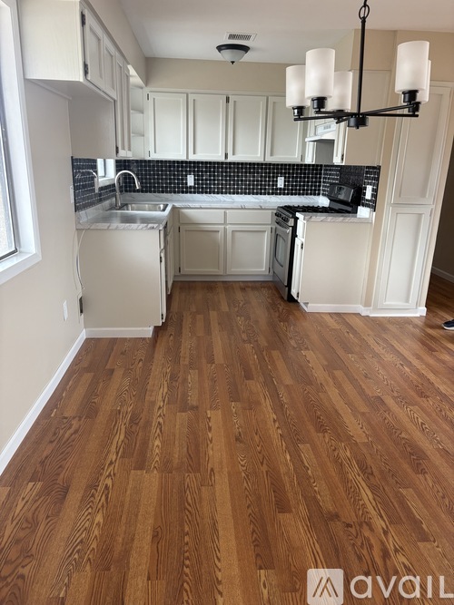A kitchen with wooden floors and white cabinets.
