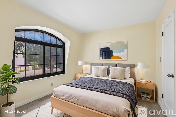 A bedroom with a large bed and a window with a view of trees.