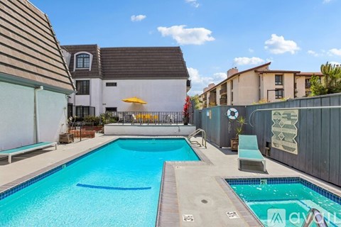 A pool surrounded by a wooden deck and a white fence.