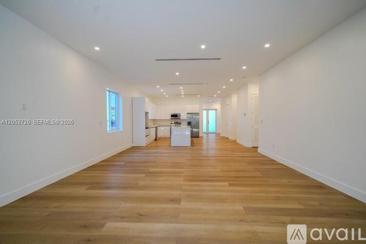 A spacious room with wooden flooring and white walls.