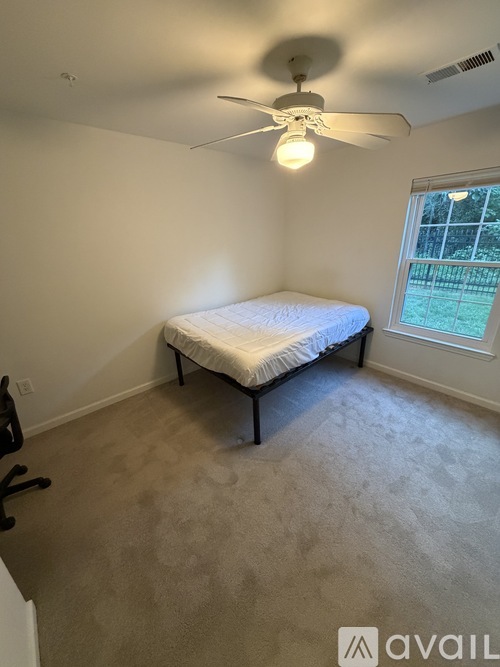 A bedroom with a bed, a ceiling fan, and a window.