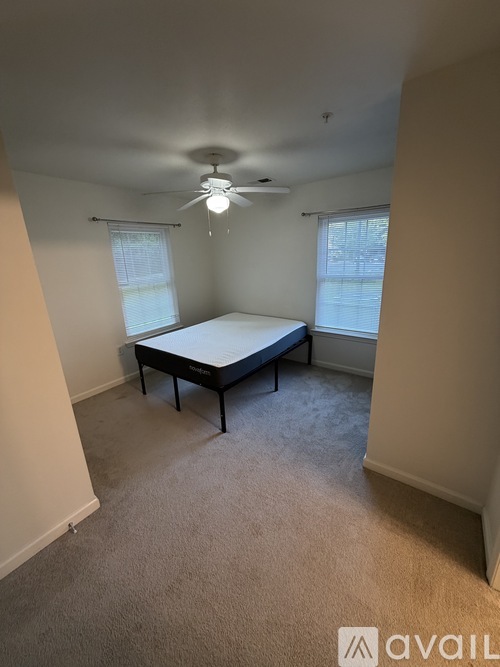 A bedroom with a bed, carpet, and a ceiling fan.