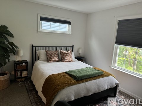 A bedroom with a large bed and a window with blinds.