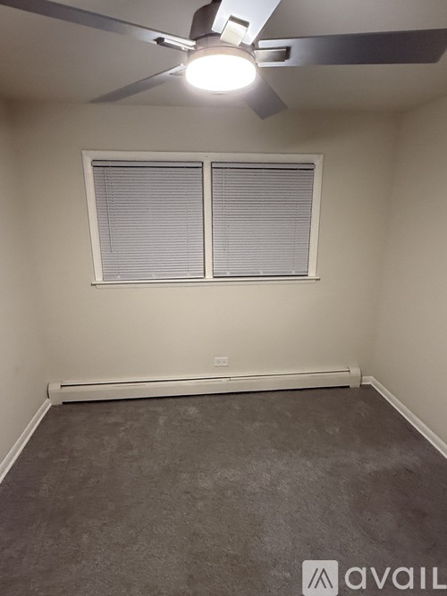 A room with a ceiling fan and a window with blinds.