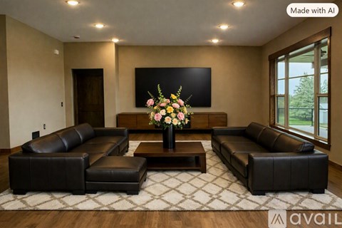 A living room with a large leather sofa set and a TV mounted on the wall.