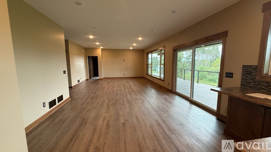 A spacious room with wooden flooring and sliding glass doors.