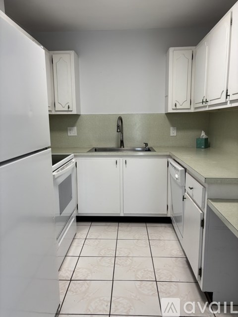 A kitchen with white cabinets and a white fridge.