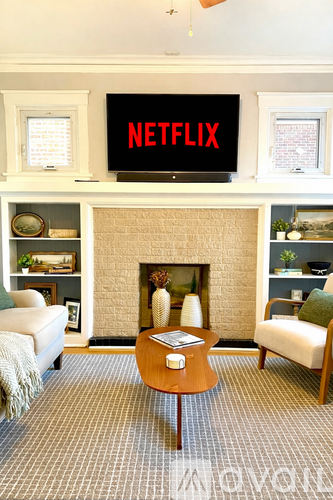 A living room with a fireplace and a TV displaying the Netflix logo.