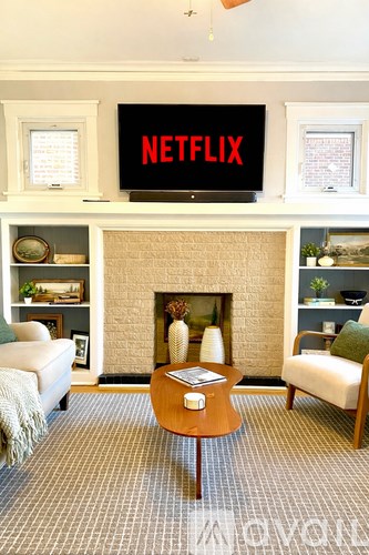 A living room with a fireplace and a TV displaying the Netflix logo.