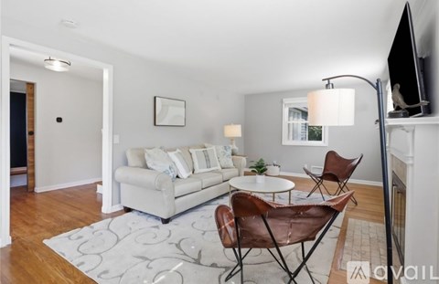 A living room with a white couch, a white coffee table, and a television on a stand.