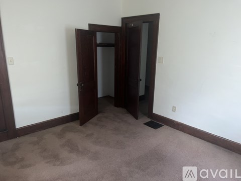 A room with a carpeted floor and two doors.