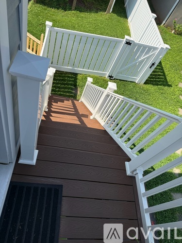 A wooden deck with a white railing and a black mat.