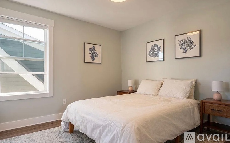 A bedroom with a large bed and two framed pictures on the wall.