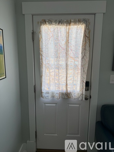 A white door with a curtain and a picture on the wall.