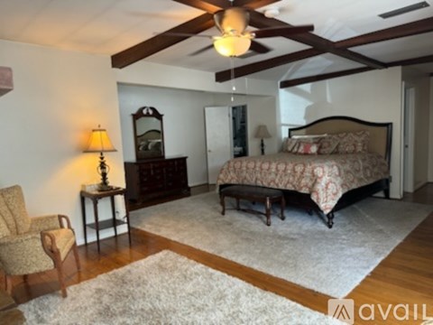 A bedroom with a large bed and a chair.
