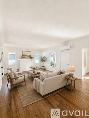 A living room with a white couch, wooden floors, and a rug.