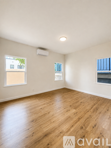 A room with wooden flooring and two windows.