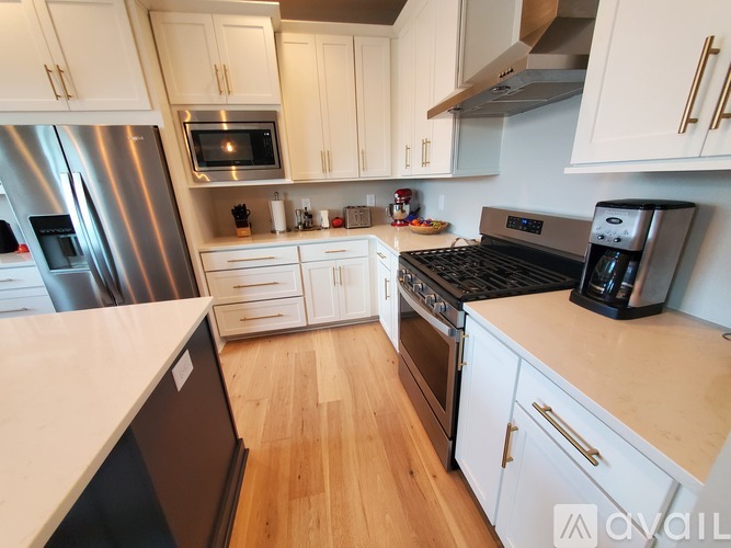 A kitchen with white cabinets and a stainless steel refrigerator.