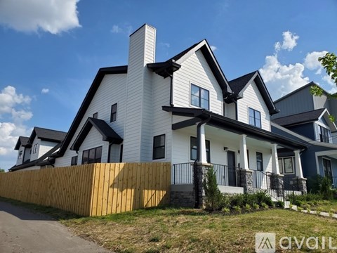 A modern house with a white and black exterior and a wooden fence.