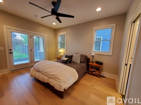 A bedroom with a bed, a ceiling fan, and a window with blinds.