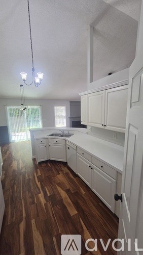 A kitchen with white cabinets and a wooden floor.