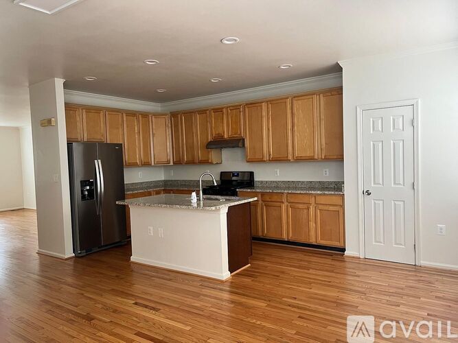 A kitchen with wooden cabinets and a black refrigerator.
