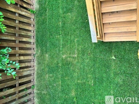 A wooden fence with green plants on the left and a wooden structure on the right.