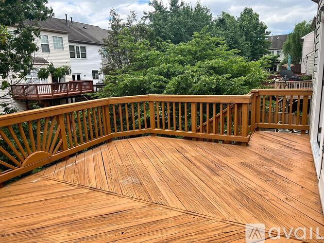 A wooden deck with a railing and trees in the background.
