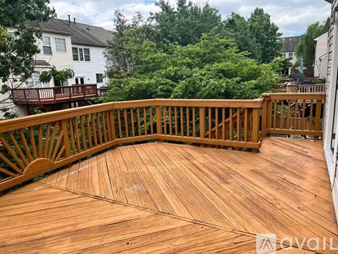 A wooden deck with a railing and trees in the background.