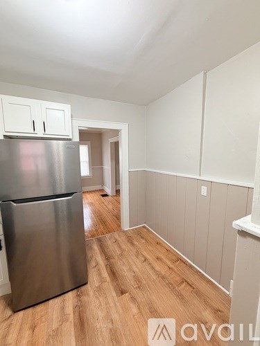 A kitchen with a stainless steel refrigerator and wooden floors.