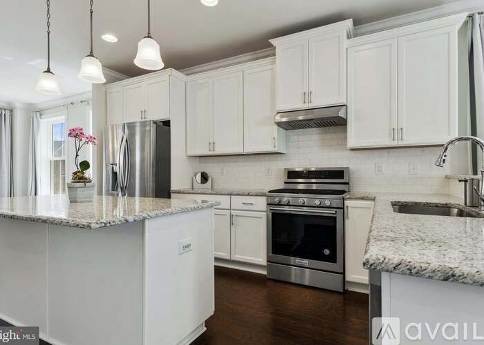 A kitchen with white cabinets and a marble countertop.