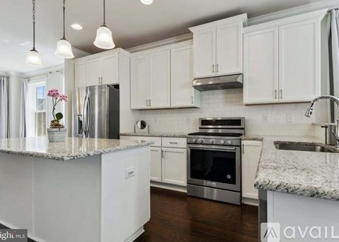 A kitchen with white cabinets and a marble countertop.