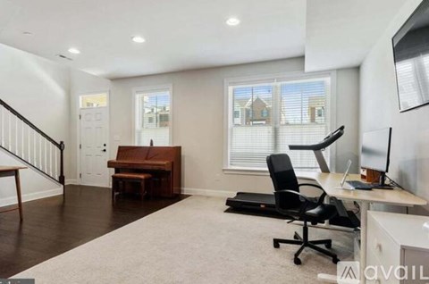 A spacious home office with a desk, chair, and a window with blinds.