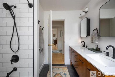 A bathroom with a white tile shower and a white sink.