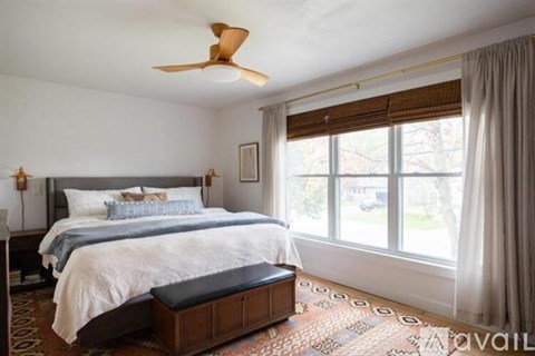 A bedroom with a large bed and a ceiling fan.
