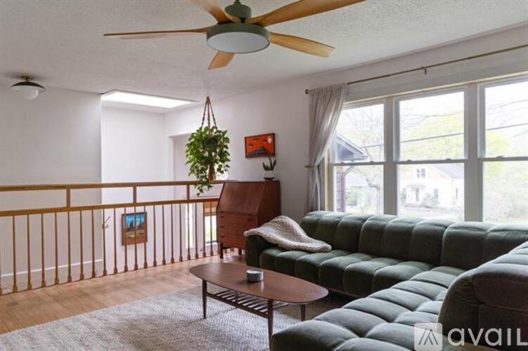 A living room with a green sofa and a ceiling fan.