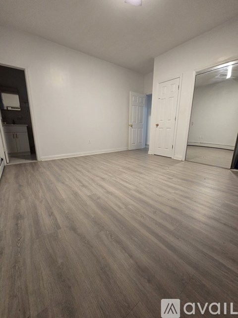 A room with wooden flooring and white walls.