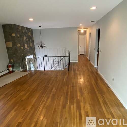 A spacious room with wooden flooring and a metal railing.