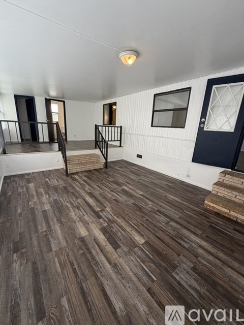 A room with wooden flooring and a staircase with a railing.