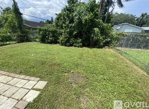 A backyard with a well-maintained lawn and a brick pathway.
