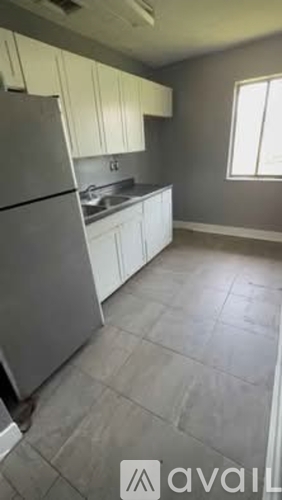 A kitchen with a refrigerator, sink, and cabinets.