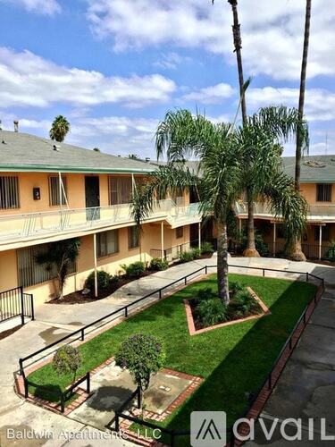 A courtyard with a palm tree and a sign that says "Baldwin Apartments LLC".