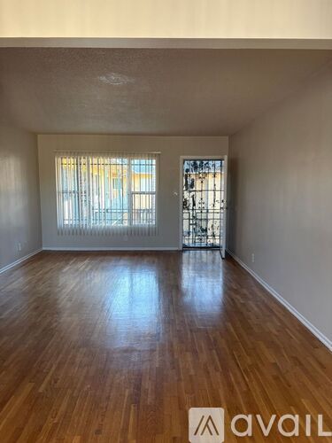 A room with wooden floors and a window with blinds.