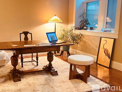 A wooden table with a laptop on it and a lamp on the side.