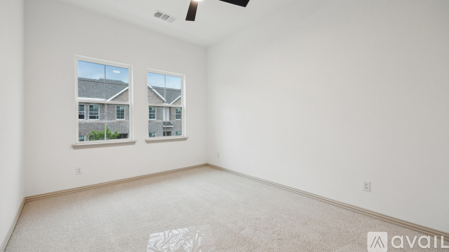 A spacious room with two windows and a ceiling fan.