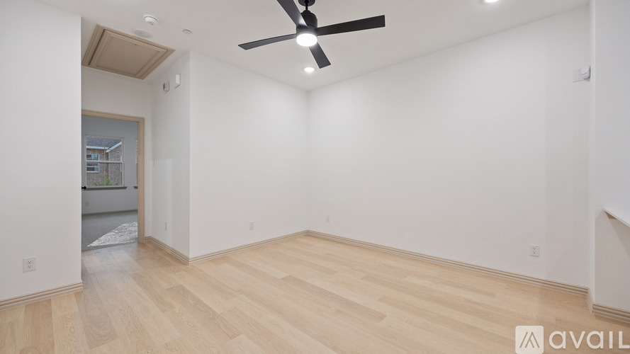 A room with a ceiling fan and wooden flooring.