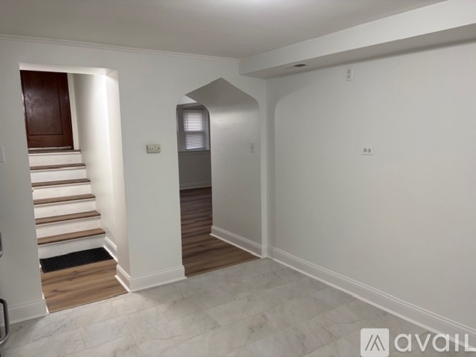 A spacious room with a staircase leading to a landing with a door.